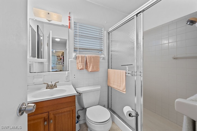 bathroom featuring walk in shower, toilet, decorative backsplash, vanity, and tile walls