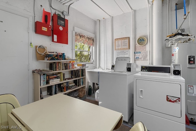 clothes washing area featuring water heater, washer and clothes dryer, and sink