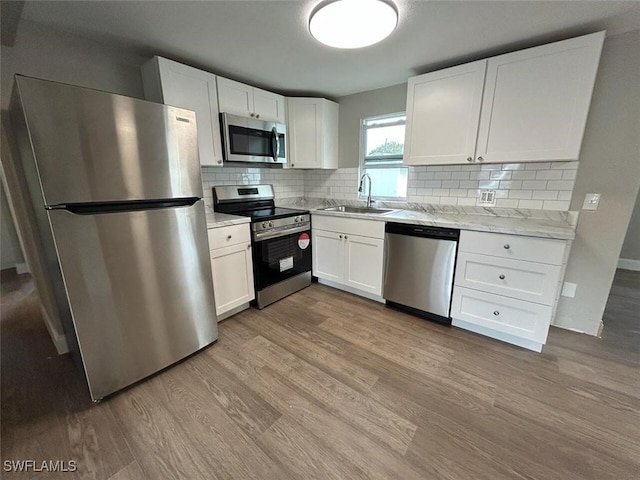 kitchen with white cabinets, stainless steel appliances, light hardwood / wood-style flooring, and sink