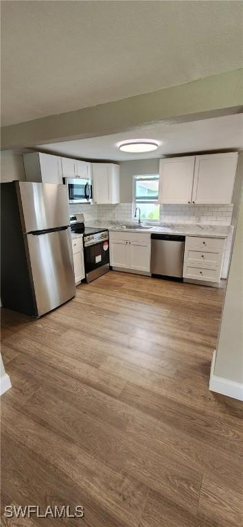 kitchen featuring decorative backsplash, light wood-type flooring, white cabinetry, and appliances with stainless steel finishes