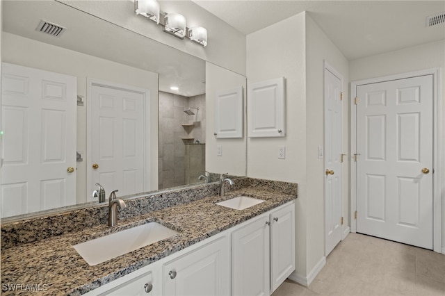 bathroom featuring double vanity, visible vents, a sink, and tiled shower