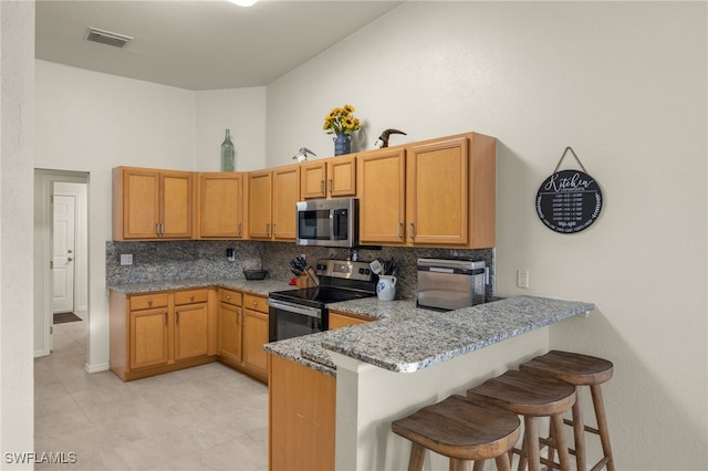3530 NE 12th Ct, Cape Coral, FL 33909 - kitchen with stainless steel appliances, decorative backsplash, light stone counters, a breakfast bar, and a towering ceiling