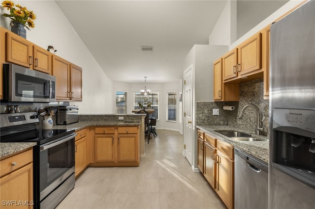 kitchen featuring visible vents, a peninsula, a sink, stainless steel appliances, and a notable chandelier