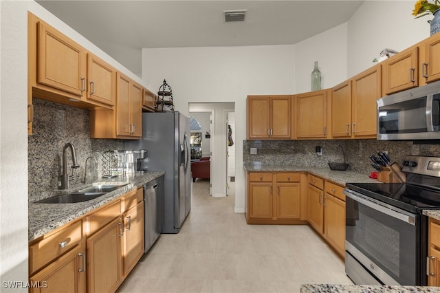 kitchen featuring light stone counters, visible vents, backsplash, appliances with stainless steel finishes, and a sink