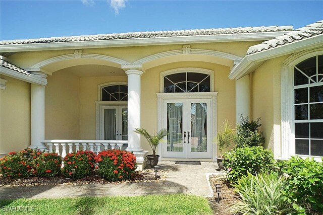 4126 SW 27th Ave, Cape Coral, FL 33914 - view of exterior entry with french doors, stucco siding, covered porch, and a tiled roof