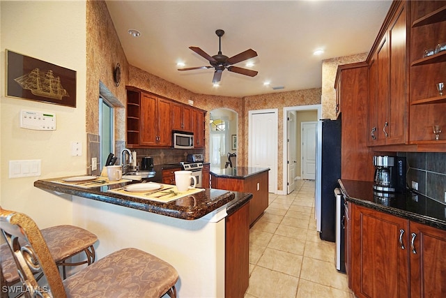 kitchen with kitchen peninsula, appliances with stainless steel finishes, a breakfast bar, ceiling fan, and sink