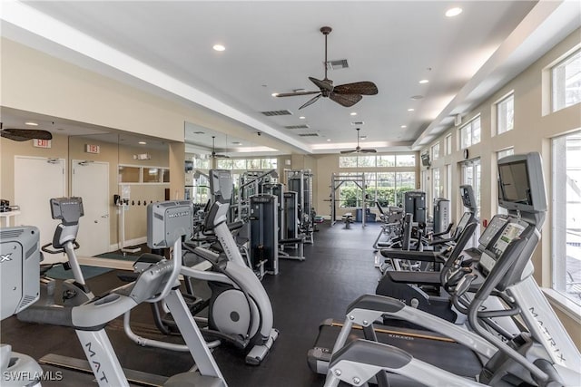 exercise room featuring ceiling fan and a tray ceiling