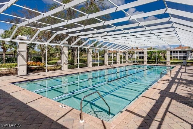 view of swimming pool featuring glass enclosure and a patio