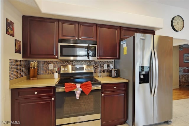 kitchen with tasteful backsplash, light tile patterned floors, and stainless steel appliances