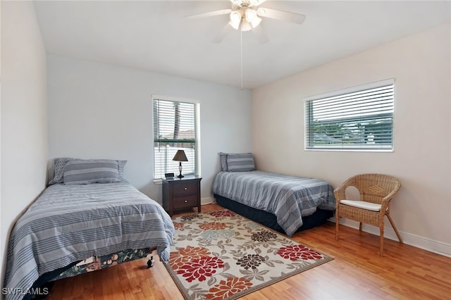 bedroom with multiple windows, ceiling fan, and hardwood / wood-style flooring