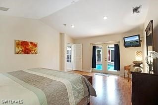 bedroom featuring access to exterior, french doors, hardwood / wood-style flooring, and vaulted ceiling