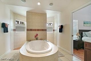 bathroom with tiled bath, tile patterned flooring, and vanity