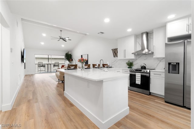 kitchen featuring backsplash, wall chimney exhaust hood, stainless steel appliances, white cabinets, and lofted ceiling