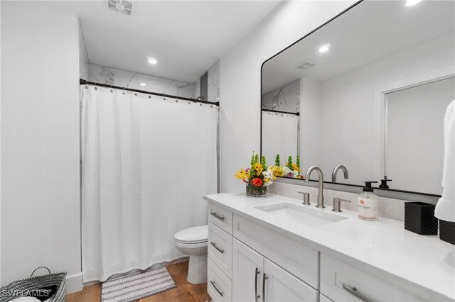 bathroom with hardwood / wood-style floors, vanity, toilet, and curtained shower