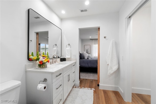 bathroom with hardwood / wood-style floors, vanity, and toilet