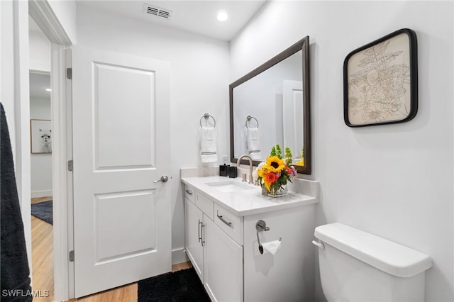 bathroom featuring toilet, vanity, and hardwood / wood-style flooring