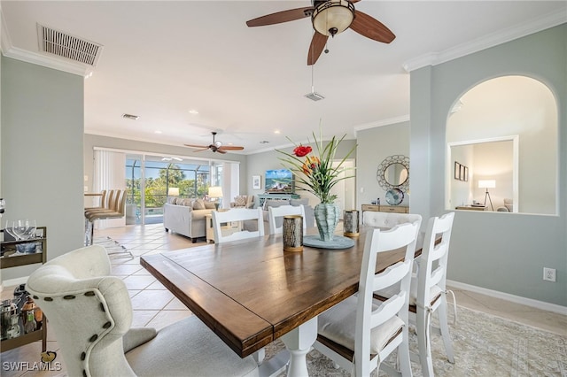 tiled dining room with ceiling fan and crown molding