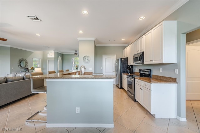 kitchen featuring appliances with stainless steel finishes, a kitchen breakfast bar, ceiling fan, white cabinets, and light tile patterned flooring