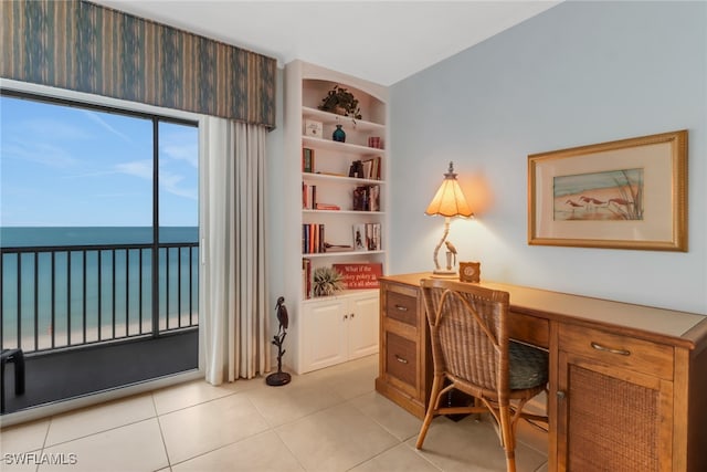 office area featuring built in features, a water view, and light tile patterned floors