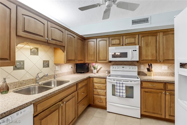 kitchen with decorative backsplash, light tile patterned floors, white appliances, and sink