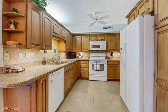 kitchen featuring white appliances, backsplash, sink, light tile patterned floors, and light stone counters