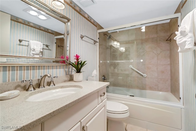 full bathroom with tile patterned floors, vanity, bath / shower combo with glass door, and toilet