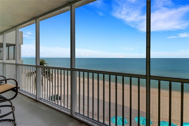 unfurnished sunroom with a water view and a view of the beach