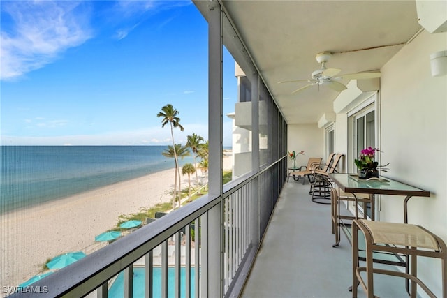 balcony with ceiling fan, a water view, and a beach view