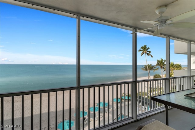 unfurnished sunroom with a view of the beach, a water view, and ceiling fan