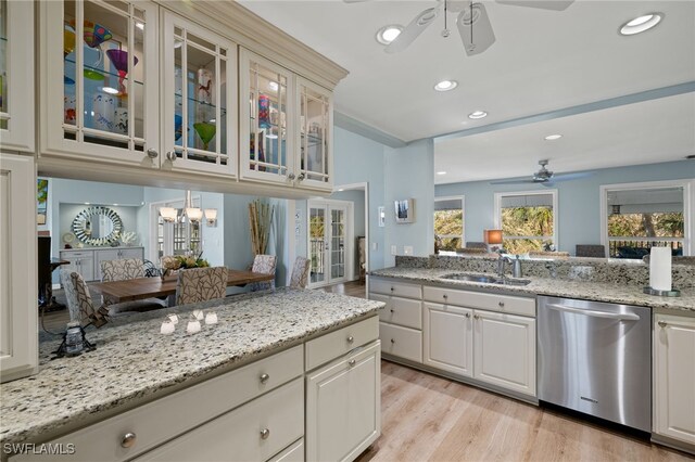 kitchen featuring light wood-style flooring, ceiling fan with notable chandelier, a sink, dishwasher, and glass insert cabinets