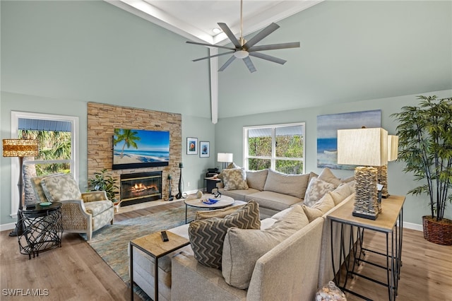 living room with a fireplace, ceiling fan, wood finished floors, high vaulted ceiling, and baseboards