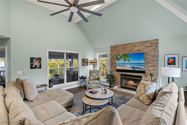 living area featuring beam ceiling, a fireplace, ceiling fan, wood finished floors, and high vaulted ceiling