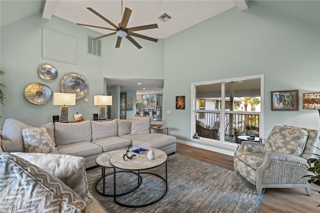 living area with visible vents, beam ceiling, and wood finished floors