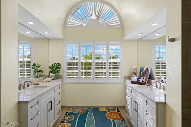 full bath with a wealth of natural light, two vanities, and a sink