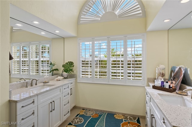 bathroom with a wealth of natural light, two vanities, and a sink