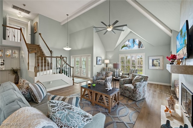 living area with a glass covered fireplace, visible vents, stairway, and wood finished floors