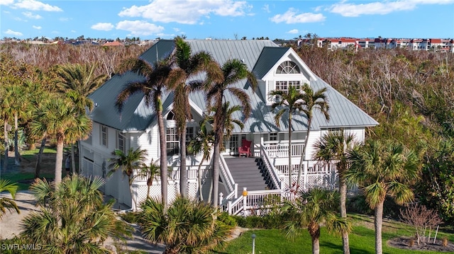 view of front of house featuring covered porch, metal roof, and stairs