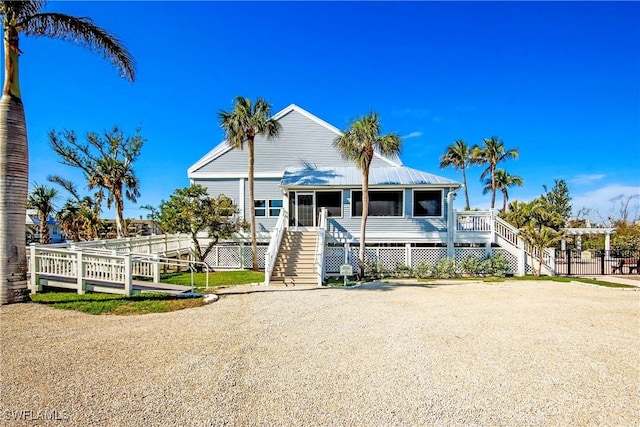 view of front of property featuring a sunroom, driveway, fence, and stairs