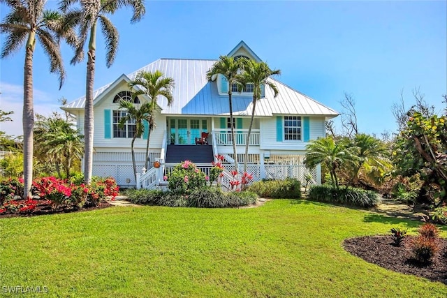 view of front of home with metal roof, a porch, stairway, and a front lawn