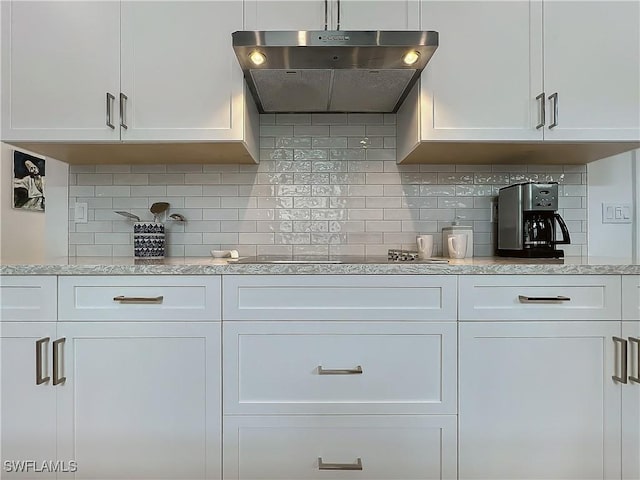 kitchen with tasteful backsplash, white cabinets, and extractor fan