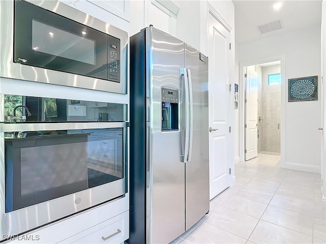 kitchen featuring light tile patterned floors, stainless steel appliances, and white cabinetry