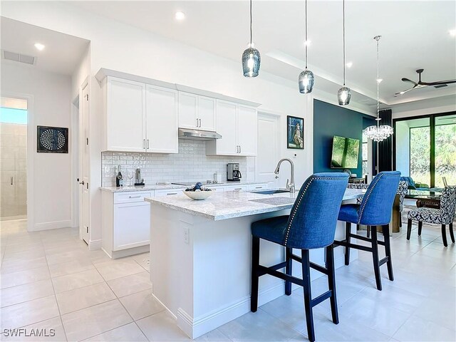 kitchen with sink, an island with sink, decorative light fixtures, white cabinets, and ceiling fan with notable chandelier