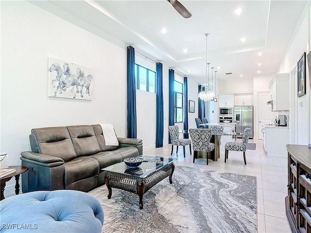 tiled living room with ceiling fan and a raised ceiling