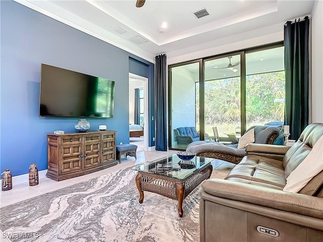 living room with ceiling fan and a tray ceiling