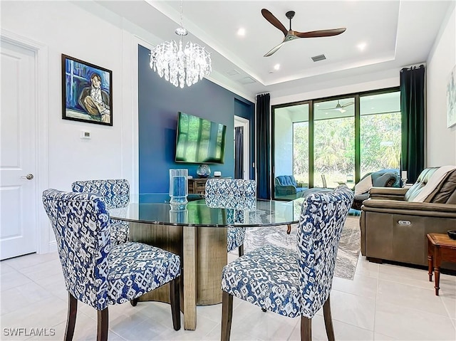 dining area with a tray ceiling, light tile patterned floors, and ceiling fan with notable chandelier