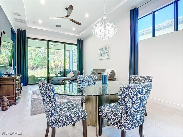 tiled dining area featuring a tray ceiling, a wealth of natural light, and ceiling fan with notable chandelier