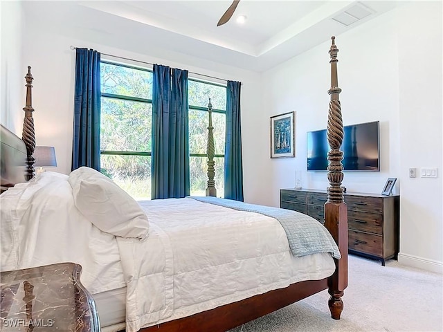 carpeted bedroom with ceiling fan and a raised ceiling