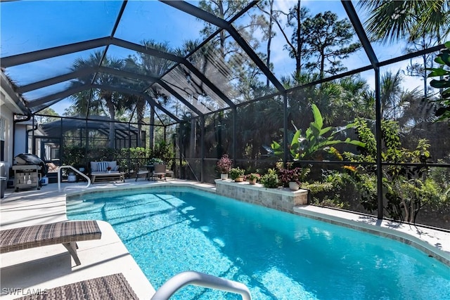 view of swimming pool featuring glass enclosure, a patio area, and grilling area