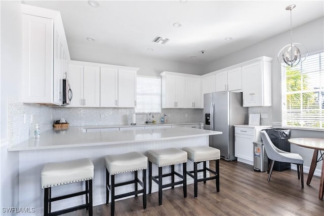 kitchen featuring a kitchen bar, dark wood-type flooring, white cabinets, and stainless steel appliances