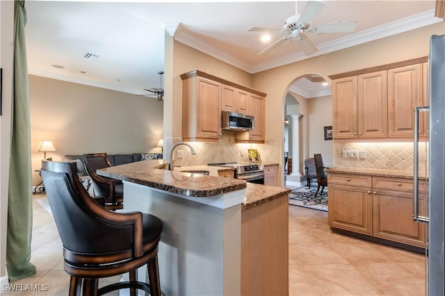 kitchen with a kitchen breakfast bar, kitchen peninsula, stone counters, and stainless steel appliances